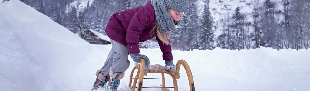 Ekokompass - bild på en lekande barn med pulka i snötäckt fjällmiljö.